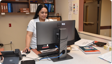 A female nurse using a computer at a nursing station