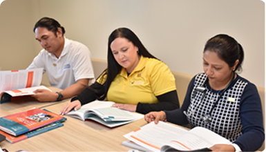 Nurses gather around the table reviewing textbooks