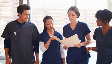 Nurses in a hospital hallway discussing a file