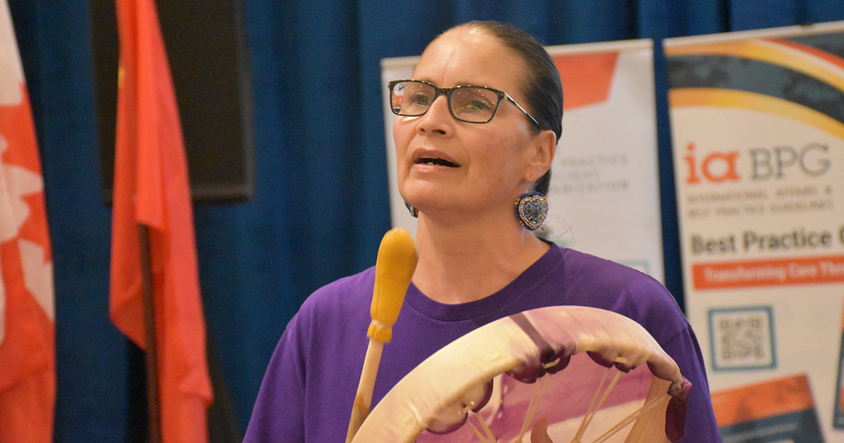 Indigenous person playing traditional hand drum as part of RNAO AGM closing ceremonies.  