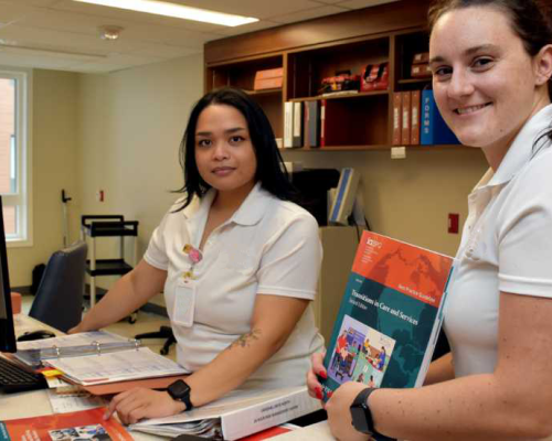 Two nurses at a nursing station with RNAO best practice guidelines