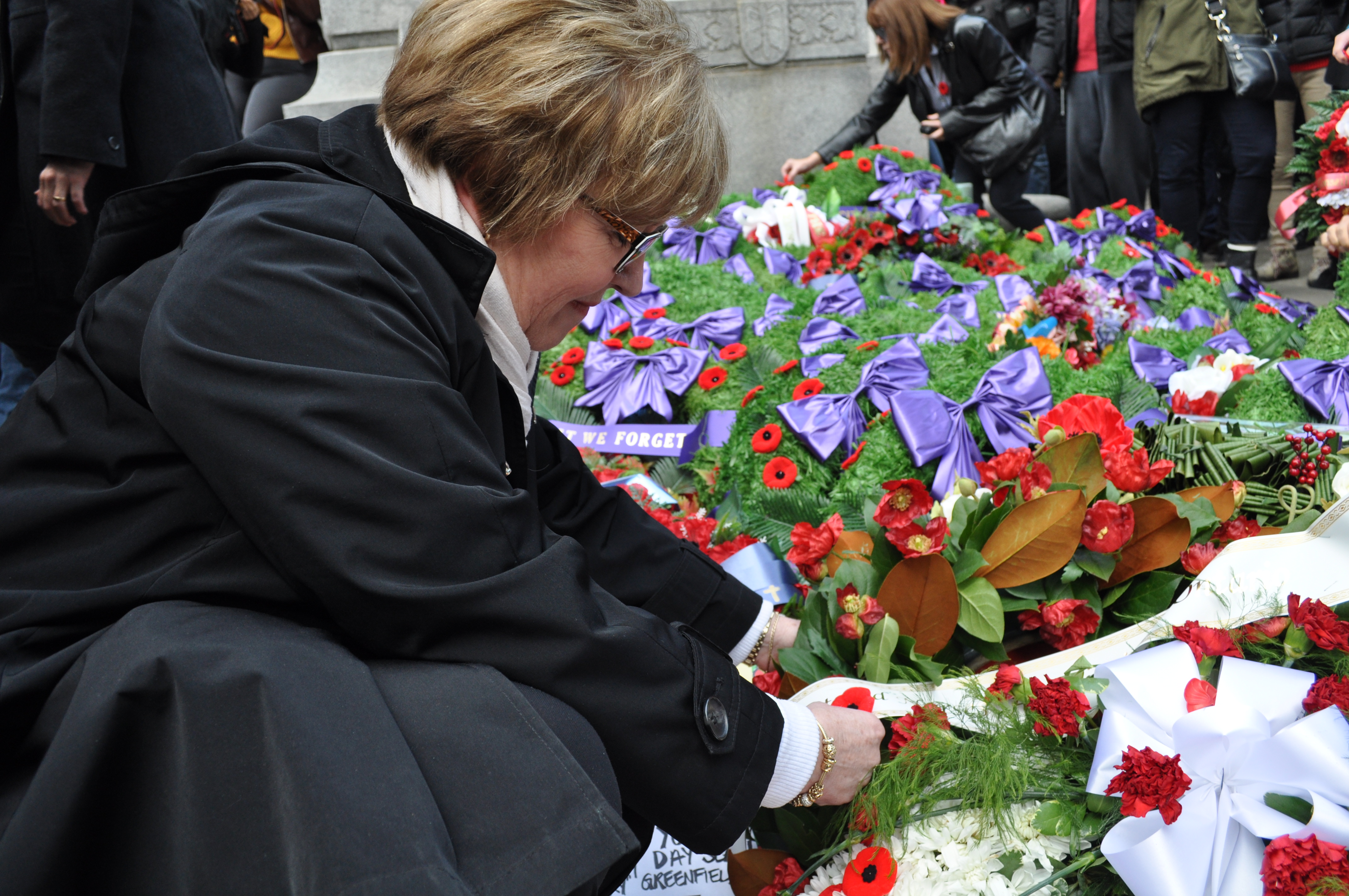 Normal Nicholson is up close looking at a white ribbon across a wreath